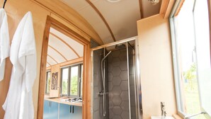 A modern bathroom with a shower, a sink, and a window. - A secluded, design-led shepherd’s hut for slow, off-grid stays by the coast (Cardigan)