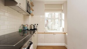 Una cucina compatta con mobili bianchi, un piano di lavoro nero e una finestra che si affaccia su edifici.