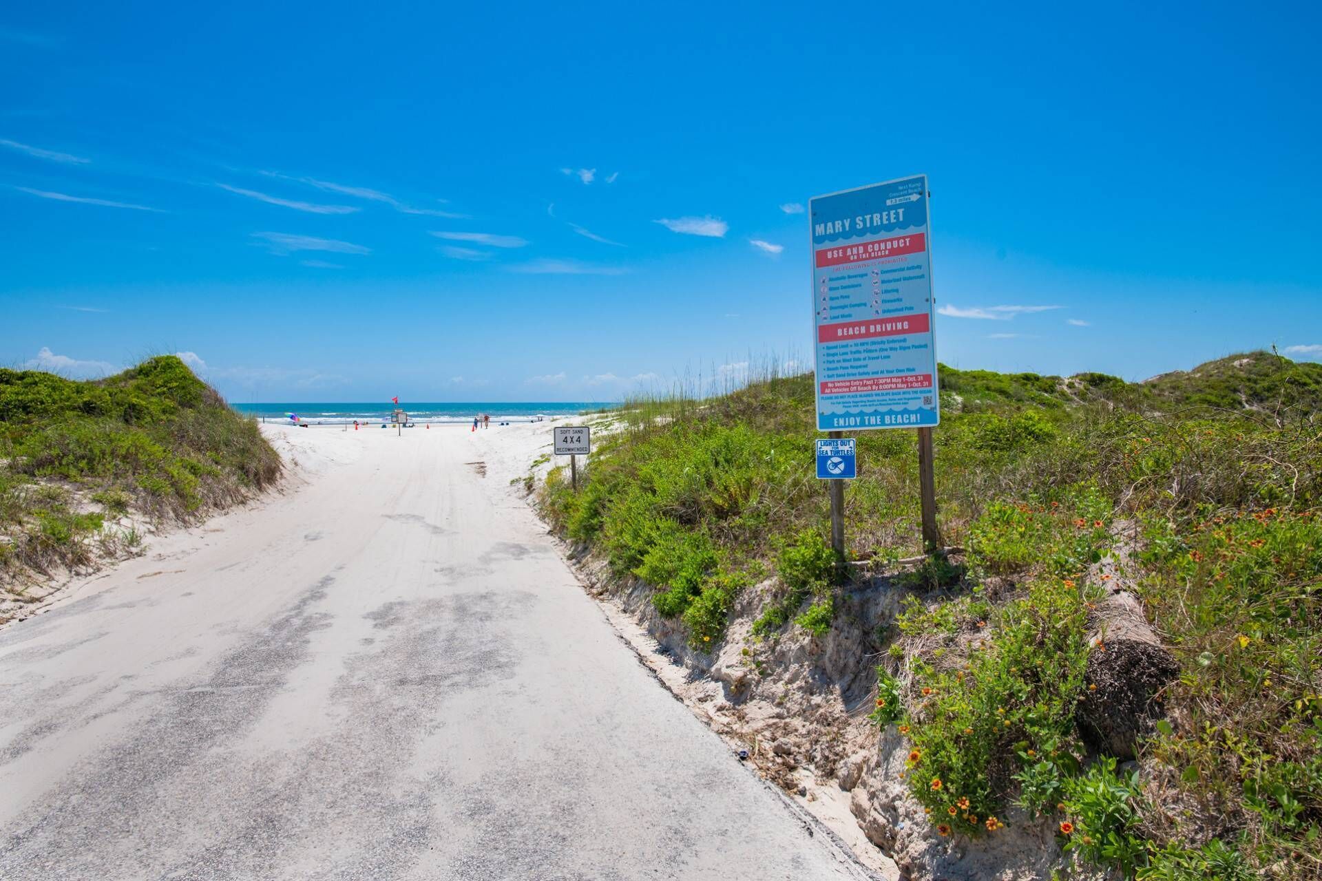 A beach road with a sign indicating 'Mary Street' and 'Beach Driving'.