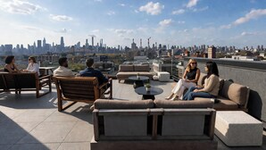 A rooftop terrace with seating arrangements, a city skyline view, and a clear sky. - Dutch Hotel Long Island City New York , Belvilla District 6 Formerly Sonder  (Long Island City)