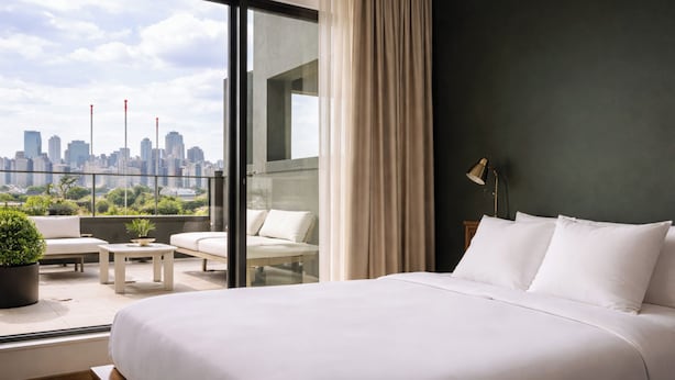 A modern hotel room with a large bed, a balcony with seating, and a city view. - Dutch Hotel Long Island City New York , Belvilla District 6 Formerly Sonder  (Long Island City)
