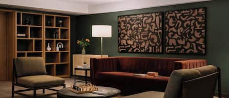 Una sala de estar moderna con un sofá, dos sillones, una mesa de centro con un juego de ajedrez, una estantería y arte abstracto en la pared.