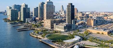 A waterfront cityscape with high-rise buildings, a marina, and a park.