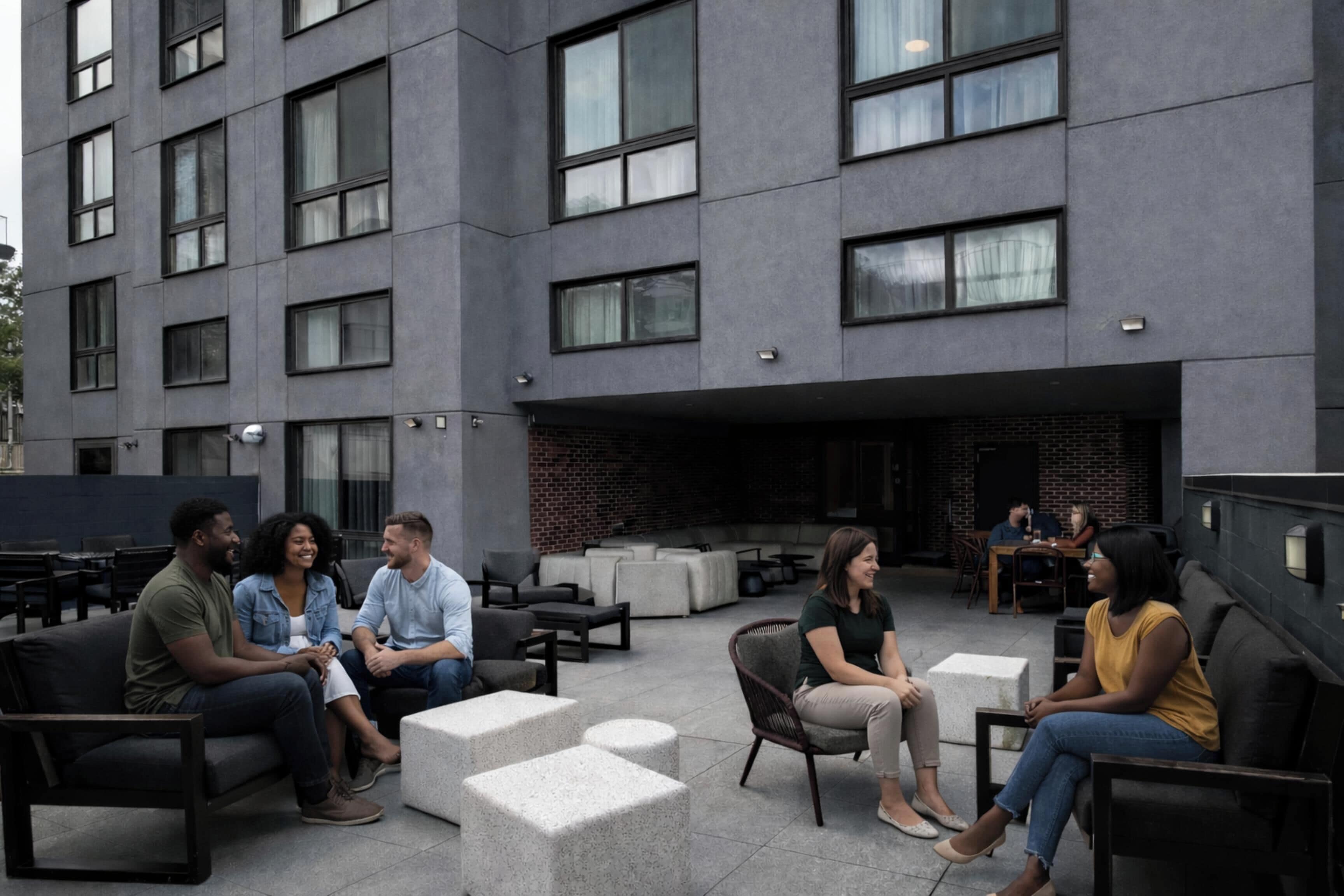 An outdoor seating area with modern furniture and a building with large windows in the background.