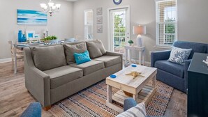 A living room with a grey sofa, a blue armchair, a wooden coffee table, and a patterned rug. - Crystal Beach Dream with Pool, Dog Park, and Beach Access (Destin)
