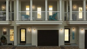 A two-story house with a covered front porch, a garage, and a brick driveway. - Crystal Beach Dream with Pool, Dog Park, and Beach Access (Destin)