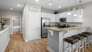 A modern kitchen with white cabinets, a stainless steel refrigerator, a microwave, and a granite countertop. - Crystal Beach Dream with Pool, Dog Park, and Beach Access (Destin)