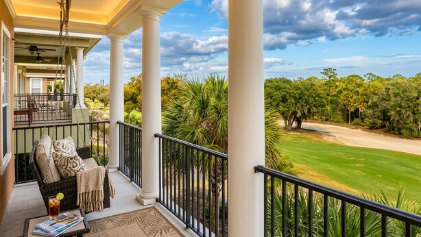 A covered porch with a swing chair, a ceiling fan, and a view of a golf course. - THE GOLF COURSE HOUSE, pet friendly, mini home theater, sleeps 18 (reunion)