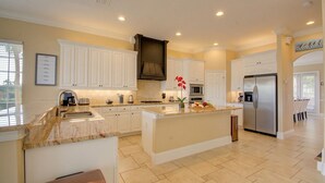 A spacious kitchen with white cabinetry, a central island, and a stainless steel refrigerator. - THE GOLF COURSE HOUSE, pet friendly, mini home theater, sleeps 18 (reunion)