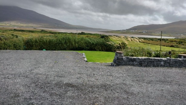 A gravel area with a stone wall and a grassy patch.