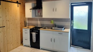 A modern kitchen with white cabinets, a black stove, and a window with frosted glass.