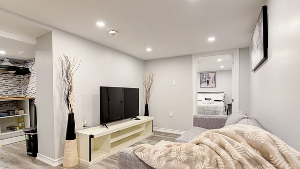 A modern living room with a flat-screen TV, a sofa, and a coffee table. - 1 Bedroom Apartment Downtown - Close to Hospital and University  (Kitchener)