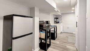 A modern kitchen with a stainless steel refrigerator, a black countertop, and a coffee machine. - 1 Bedroom Apartment Downtown - Close to Hospital and University  (Kitchener)