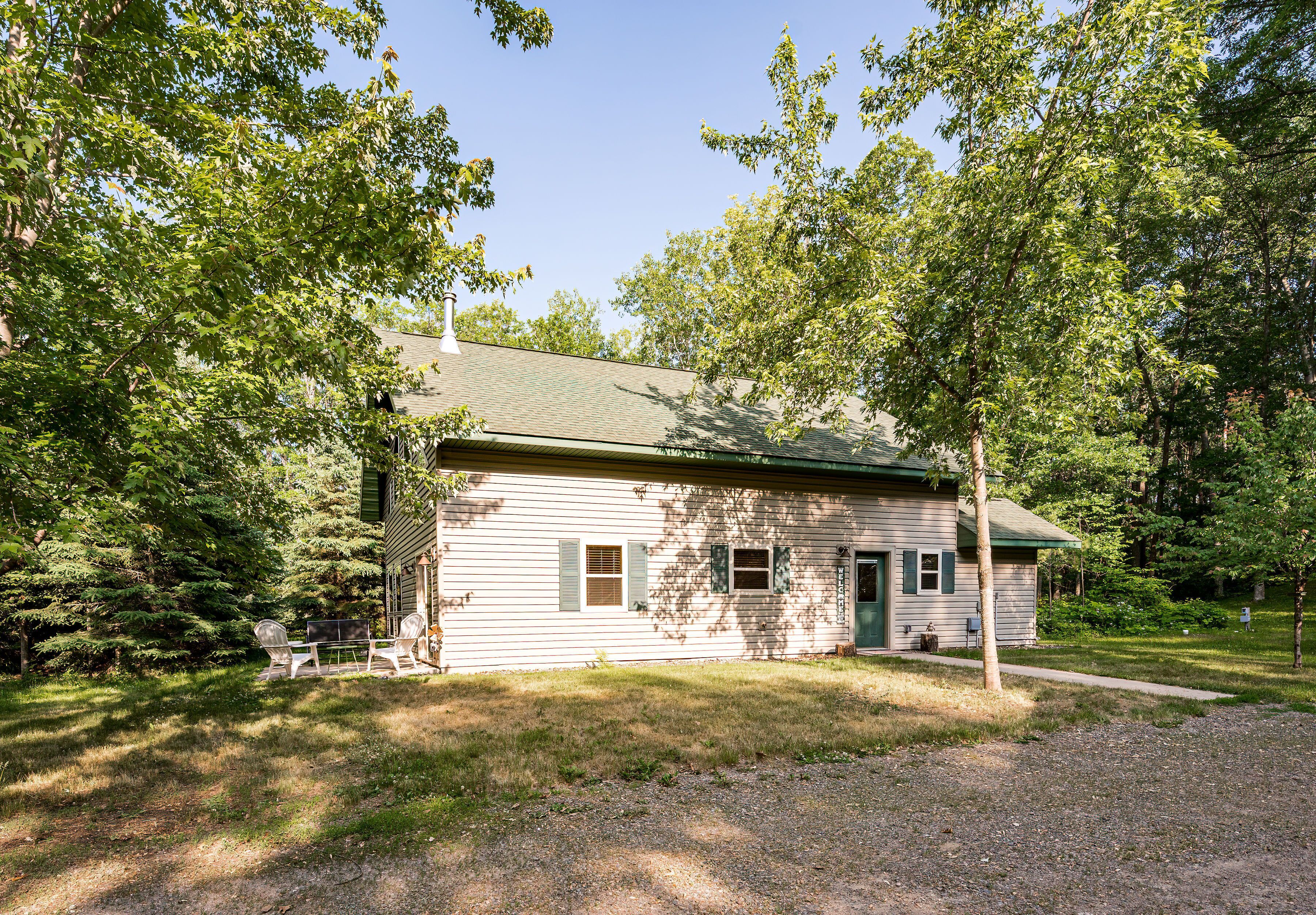 A small, single-story building with a green roof, surrounded by trees and a grassy yard.