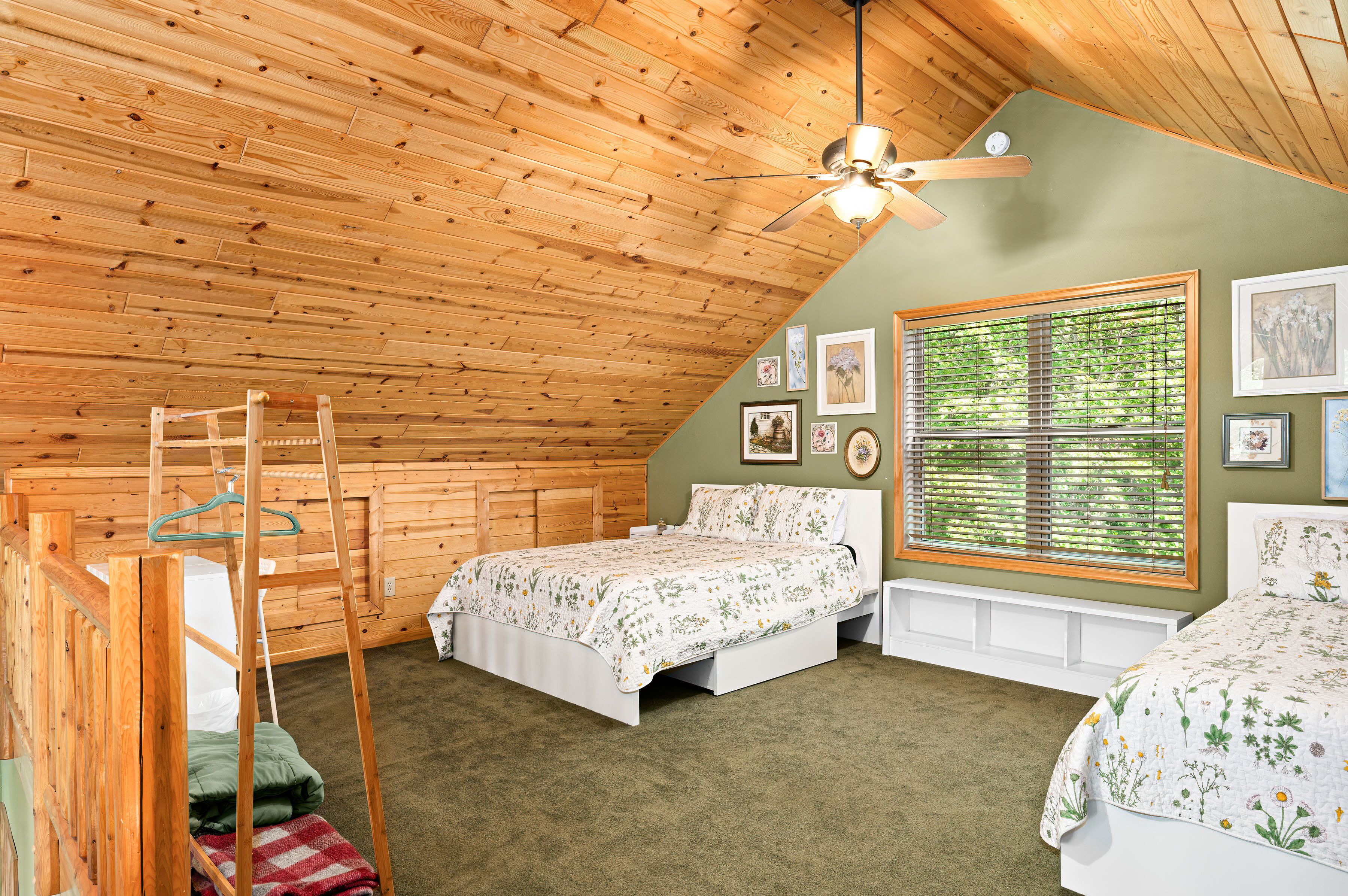 Un dormitorio acogedor en el ático, con techo de madera inclinado, una cama, un banco y una ventana con persianas.