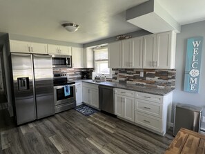 A modern kitchen with stainless steel appliances, white cabinetry, and a welcome sign. - COVE DISTRICT HOUSE WITH VIEW OF CEDAR POINT (Sandusky)