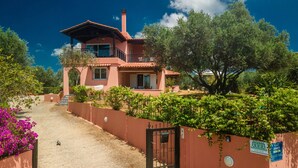 Uma casa de dois andares com fachada vermelha, uma varanda e um portão.