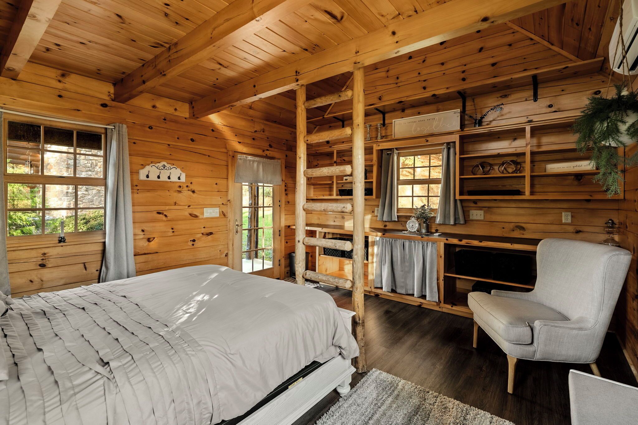 Ein Holzblockhaus-Innenraum mit Bett, Stuhl, Schreibtisch und Regalen.