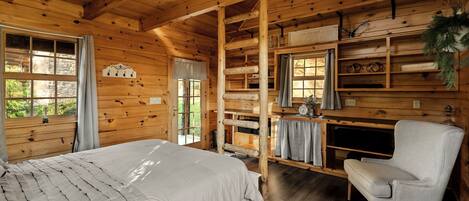 Ein Holzblockhaus-Innenraum mit Bett, Stuhl, Schreibtisch und Regalen.