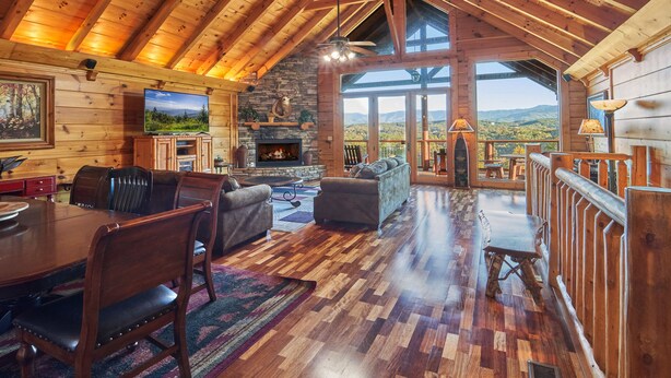 A spacious wooden cabin with a fireplace, a dining area, and a balcony with a mountain view. - Big Thunder Lodge: 180 Degree Views, 2 Kitchens (Sevierville)