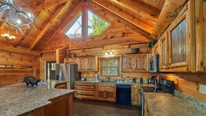 A spacious kitchen with wooden cabinets, granite countertops, and a large island. - Big Thunder Lodge: 180 Degree Views, 2 Kitchens (Sevierville)