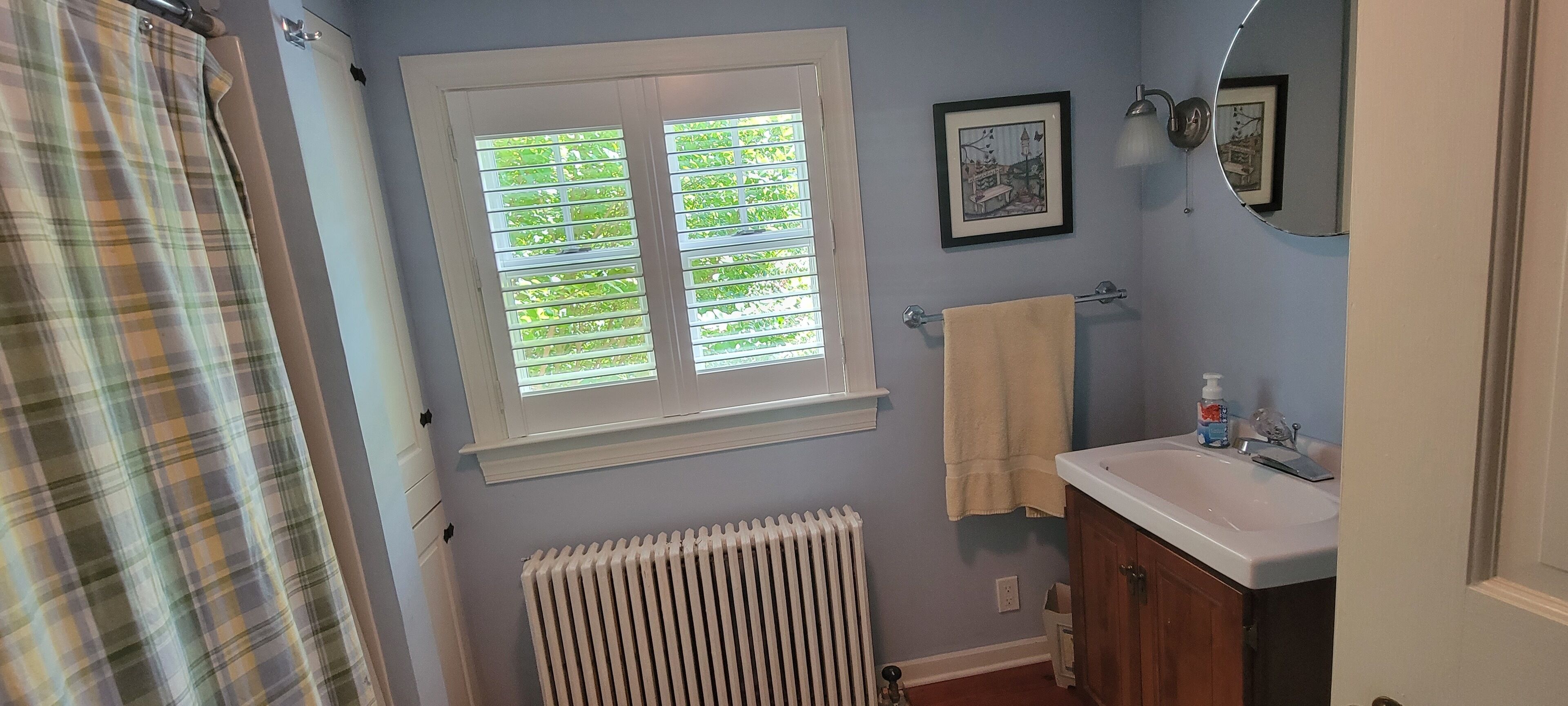 Un baño con ventana, radiador, lavabo y toallero.