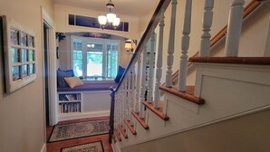Una escalera con balaustres blancos y barandilla de madera que lleva a una plataforma.