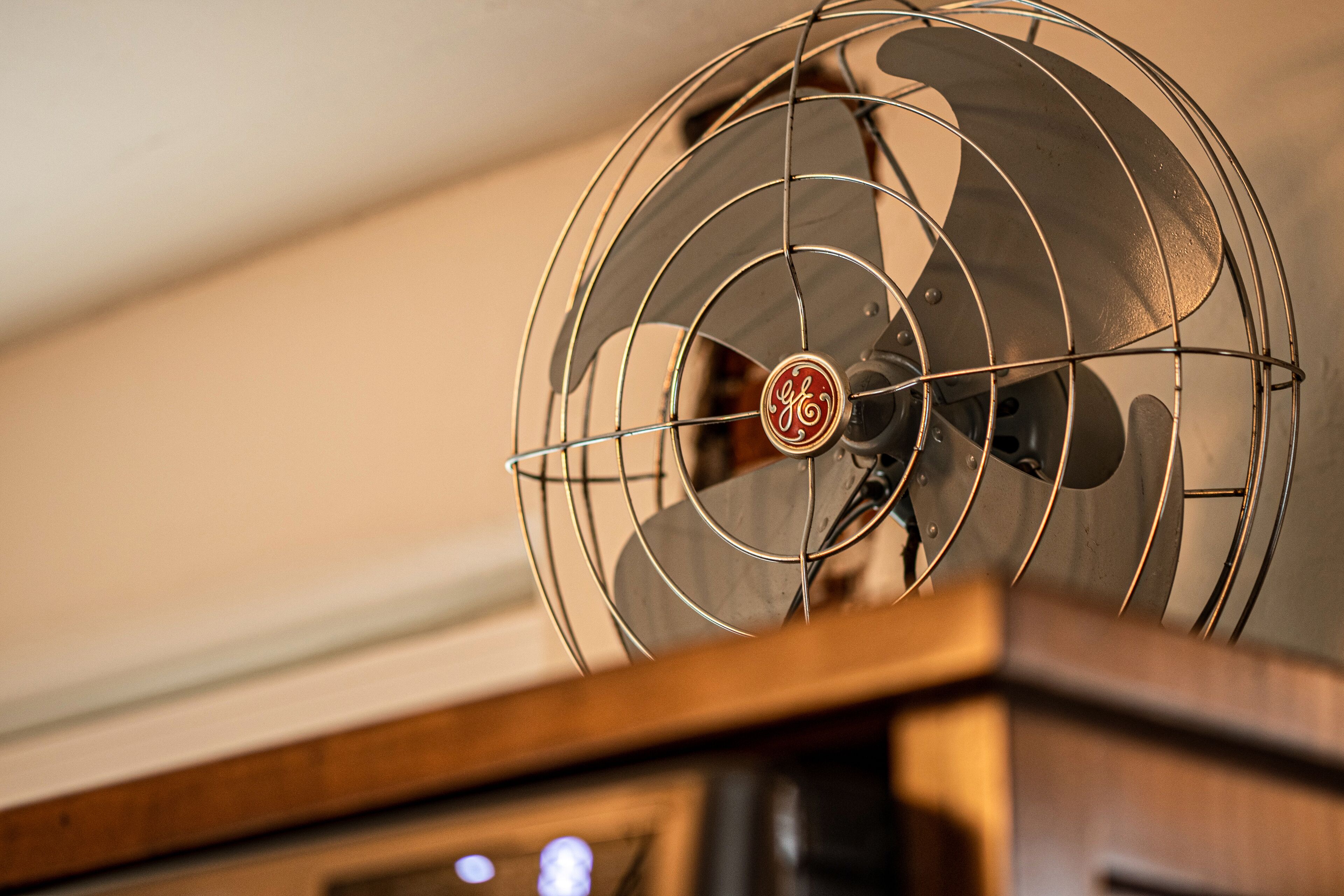 A GE brand fan with a wooden base, likely part of a room's ventilation system.