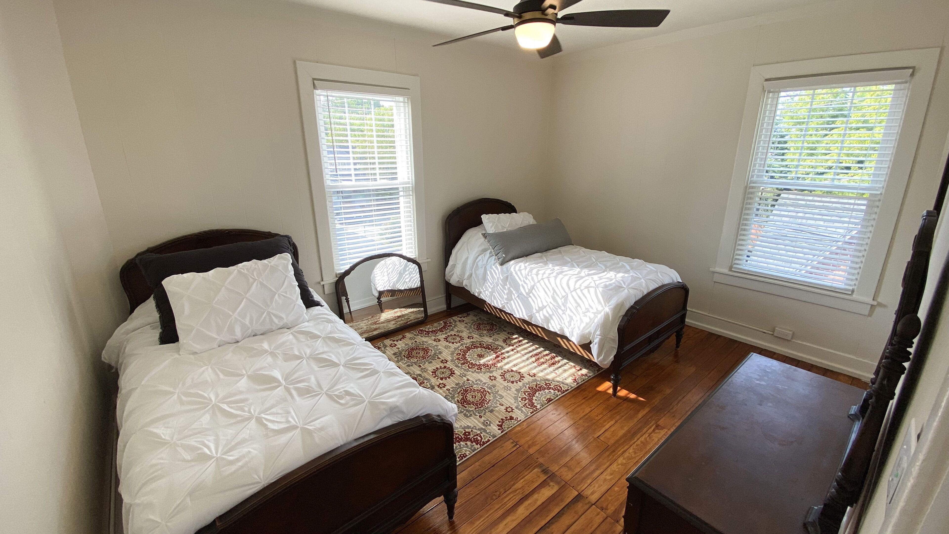A bedroom with two single beds, a ceiling fan, and a wooden floor.