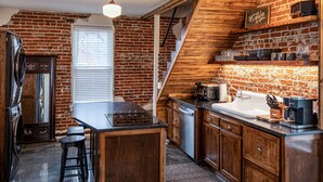 Una cocina con pared de ladrillo, armarios de madera, estufa y lavamanos.