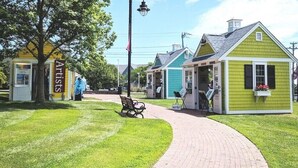 A pathway leading to a row of artist studios with a bench and a signboard. - Charming cottage in Hyannis walk to downtown, beach, Harbor, pet friendly fence (Barnstable)