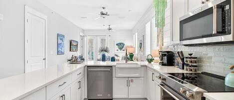 Una cocina moderna con armarios blancos, estufa de acero inoxidable, microondas y lavavajillas.