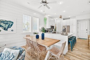 A modern kitchen with white cabinetry, a wooden island, and bar stools. - Blue Lagoon TC 10102 (Port Aransas)