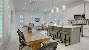 A modern kitchen with a central island, bar stools, and a dining table. - Pecan Pie 236 BR (Port Aransas)
