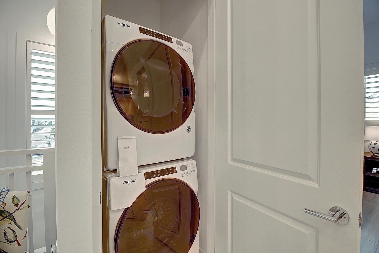 A laundry room with two stacked Whirlpool front-loading washing machines.
