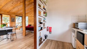 Un interior de madera con comedor, cocina y estanterías con diversos objetos.
