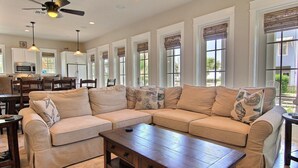 A spacious living room with a beige sectional sofa, a wooden coffee table, and a ceiling fan. - Sea Star 104 ST (Port Aransas)