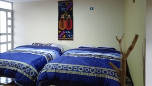 A room with two beds, a wall hanging, and a wooden branch.