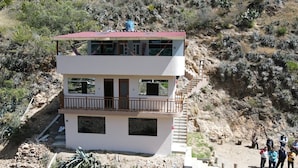 A two-story building with a red roof, a balcony on the upper floor, and a staircase leading to the upper level.