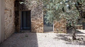 Un edificio de piedra con una puerta y un pequeño árbol en primer plano.