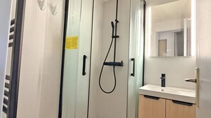Ein Badezimmer mit Dusche, Waschbecken und Spiegel.