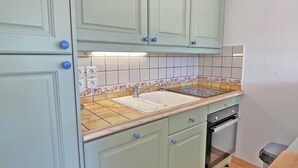 A kitchen with light green cabinets, a tiled backsplash, a sink, and a dishwasher. - Apartment for 4/6 people – Swimming pool residence – Air conditioning – WiFi – Sainte Maxime (STE MAXIME)