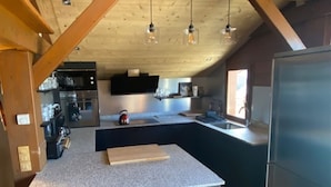 A modern kitchen with a central island, dark cabinetry, and a stainless steel refrigerator. - 14 person chalet, 100m from the Super-Chatel gondola - Chatel Reservation (Châtel)