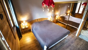 A bedroom with a wooden headboard, a bed with a grey mattress, bedside lamps, and a red hanging light fixture. - 14 person chalet, 100m from the Super-Chatel gondola - Chatel Reservation (Châtel)