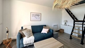 Ein modernes Wohnzimmer mit einem blauen Sofa, einem Holztisch, einer Hängeleuchte und einer Treppe.