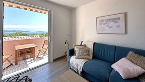 Ein modernes Wohnzimmer mit einem blauen Sofa, einem Holztisch und Stühlen vor einer Glasschiebetür.