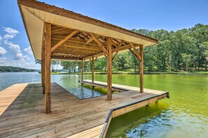 Eine Holzsteg, der sich in einen See erstreckt, mit einer überdachten Pavillon-Struktur.