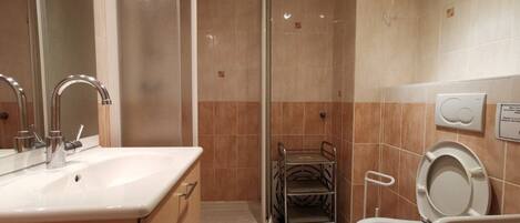 Ein Badezimmer mit Waschbecken, Spiegel, Toilette und Duschkabine.
