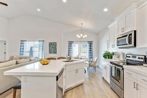 A modern kitchen with white cabinets, a central island, and stainless steel appliances. - Spacious Retreat for Unforgettable Gatherings! (Vineyard)