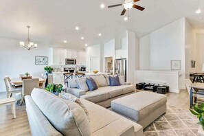 A modern living room with a sofa set, a dining area, and a kitchen in the background. - Spacious Home for Amazing long term stays! (Vineyard)